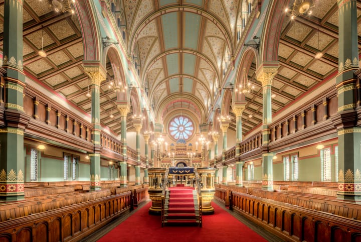 Synagogue interior with seating on both sides and bema in the middle of the central aisle