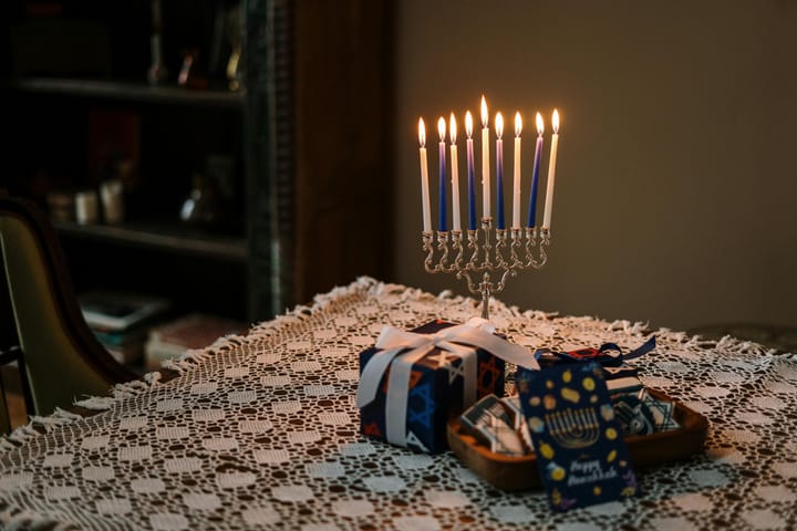 Table with a lit menorah and wrapped gifts